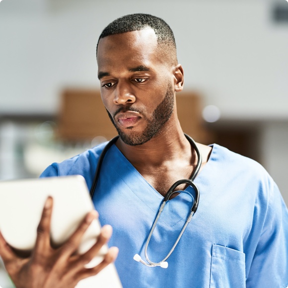 Male medical professional looking at tablet - Learning Management HealthStream
